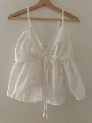 Vit broderad linnetopp med snörning - Superfin vit linne med broderade blommor och justerbara smala axelband och, snörning framtill! Passar till alla tillfällen ☀️Storlek S/M 