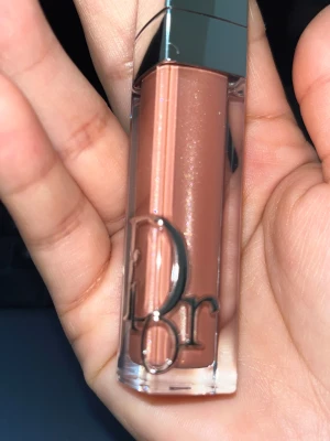 Dior Addict Lip Maximizer Shimmer Macadamia - Dior Addict Lip Maximizer i färgen 014 Shimmer Macadamia. Ett lyxigt läppglans med volymgivande effekt och skimrande finish. Färgen är en varm nude med subtilt guldskimmer. Snygg förpackning med silverlock och Dior-logga i metall på genomskinlig plast.