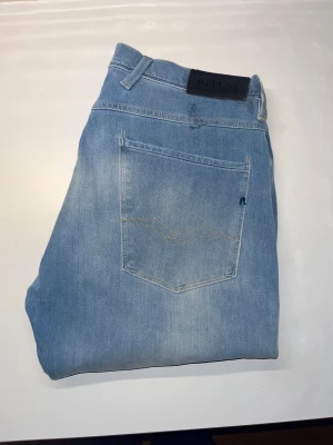 Replay Hyperflex Anbass jeans - Säljer ett par Replay Hyperflex Anbass jeans i ljusblå tvätt. Modellen har smal passform med stretchigt material som ger grym komfort. Midja 41cm, längd 112cm.JAG SKICKAR EJ FLER BILDER NÄR JAG BÄR JEANSEN! för storleksguide hänvisar jag till måtten och för bättre inblick i passformen rekommenderar jag att googla på modellnamnet. kolla måtten noggrant :) s3 