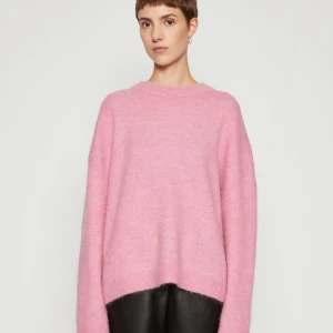 Oversized rosa stickad tröja - Mysig oversized stickad tröja i ljusrosa färg liknande den på bilden. Tröjan har en enkel rund halsringning och långa ärmar, perfekt för lager på lager. Den är mjuk och har en avslappnad passform som ger en chill vibe. Tröjan är från H&M.