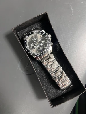 Silverfärgad klocka från Hugo Boss - Stilren klocka från Hugo Boss med silverfärgat armband i metall och blå urtavla. Klockan har tre mindre urtavlor, tydliga markeringar och klassisk rund form. Perfekt accessoar för dig som gillar en modern och elegant look.