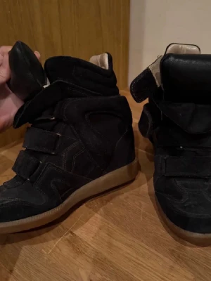 Svarta höga sneakers med kardborre - Säljer ett par isabel marant skor då jag är sugen på en annan färg! Dom är använda men i fint skick men sulan inuti skorna har defekter men annars är dom super fina!❣️