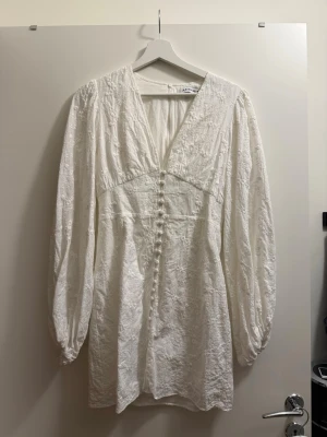 Adoore Positano klänning - vit kortklänning från Adoore. Ärmarna är omsydda och det saknar 4st knappar, använd 1 gång. Inga fläckar eller liknande