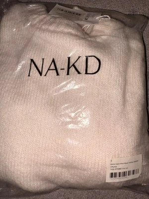 Vit stickad tröja från NA-KD - Säljer en krämvit stickad tröja från NA-KD med rund halsringning. Tröjan är stickad och har en mjuk, mysig känsla. Materialet är en ullblandning. I orginalförpackning samt med prislapp. Säljes då jag missade returtiden. Originalpris 399kr