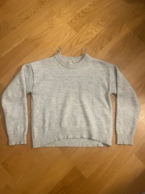 Ljusgrå stickad tröja i ullmix - Mysig ljusgrå stickad tröja med rund halsringning och ribbade muddar vid ärmslut och nederkant. Är tillverkad i en mjuk ullblandning. Perfekt för lager på lager under kyliga dagar.💕
