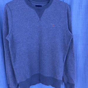 Blå sweatshirt från Gant - Klassisk blå sweatshirt från Gant med rund halsringning och ribbade muddar vid ärmslut och nederkant. Liten broderad logga på bröstet. Perfekt till jeans eller chinos för en avslappnad stil. Skriv om ni har några frågor 🤝😄