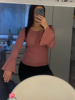Rosa ribbad topp med utsvängd ärm - Supersöt rosa ribbad tröja med utsvängda volang-ärmar från Gina Tricot.Toppen är figurnära och passar lika bra till vardags som på fest. Går utmärkt att klä upp eller ner utifrån tillfälle. 