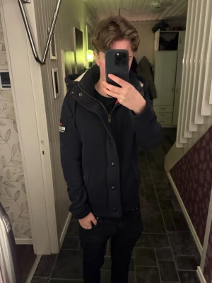  Hollister tröja - Svart hoodiejacka från Hollister med dragkedja och knappar framtill. Jackan har huva med mysigt foder och två fickor. Hollister-logga på ärmen och röd insida. Perfekt för kyliga dagar. Lite blekt på armbågarna samt lite i kragen men syns typ bara på kamera. Lite hårig löser de innan ja skickar 
