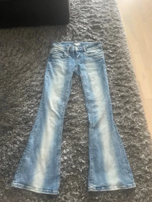 Blå bootcut jeans från Gina Tricot - Snygga ljusblå bootcut jeans från Gina Tricot med klassisk femficksdesign och utsvängda ben. Jeansen har en cool tvättad look och passar perfekt till en trendig vardagsstil. Tillverkade i jeansmaterial med bekväm passform.