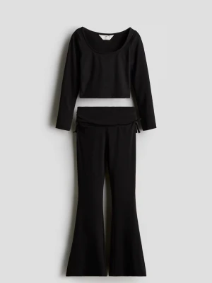 Svart set med långärmad topp & byxor - Säljer ett svart set med långärmad, croppad topp och matchande utsvängda byxor med låg midja och knyt i sidorna. Prislappen är kvar. Satt lite för tajt på mig, känns liten i storleken då jag brukar kunna ha strl 170! Ordinarie pris 250kr. 