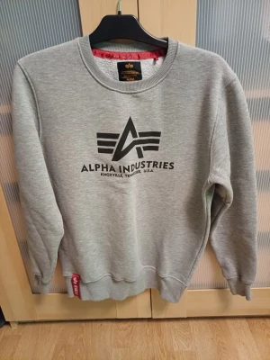 Alpha industries swetshirt stl S - En grå sweatshirt i stl S. Bra passform med skönt material. Använd en del men ändå i bra skick. Köpt för 700 kr 2022