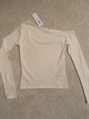 Offshoulder ribbad topp från Gina Tricot 14+ - Trendig offshoulder topp från Gina Tricot 14+ i vitt ribbat material. Långärmad och figurnära passform. Prislapp kvar, oanvänd. Liten i storleken.