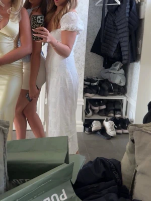 Vit långklänning med puffärm - Romantisk vit långklänning med broderade detaljer och puffärmar. Klänningen har fyrkantig ringning och smockad överdel, vilket ger en söt och trendig look. Perfekt för sommarens alla tillfällen. Student och midsommar 