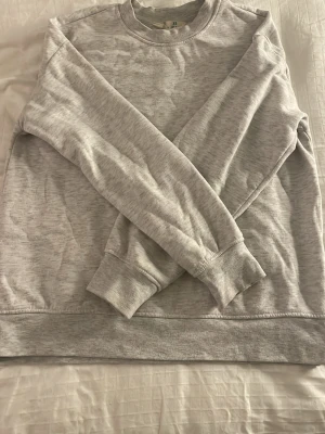 Ljusgrå sweatshirt från primark - En basic ljusgrå sweatshirt från Primark i mjukt bomullsmaterial. Tröjan har rund halsringning, långa ärmar och ribbade muddar vid ärmslut och nederkant. Knappt använd 