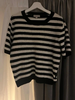 Randig svartvit topp med kort ärm - Snygg topp med svarta och vita horisontella ränder. Modellen har korta ärmar, rund halsringning och ribbade kanter. Materialet känns mjukt och lite fluffigt, perfekt för en chill och stilren look.🙌🏻🙌🏻