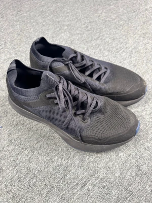 Uniqlo Skor - Snygga svarta sneakers med ovandel i mesh och detaljer i textil. Skorna har svarta skosnören och en blå, mönstrad yttersula som ger extra grepp. Perfekta för dig som gillar en sportig och clean look.