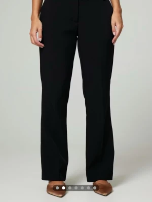 Svarta flare kostymbyxor - Stilrena svarta kostymbyxor med lite flare och pressveck. Byxorna har midwaist och bälteshällor, perfekta för en clean och klassisk look. 