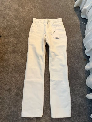 Vita straight jeans från Pull&Bear - Snygga vita jeans från Pull&Bear i rak modell med mid rise och full längd. Klassisk femficksdesign och silverfärgade detaljer. Aldrig använda