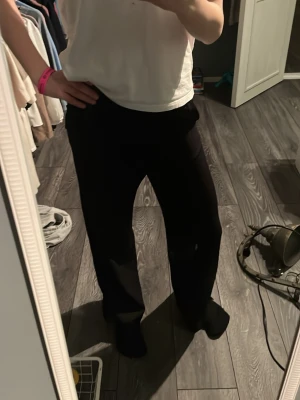 Svarta kostymbyxor med rak passform - Säljer ett par svarta kostymbyxor med rak passform och hög midja. Byxorna har en klassisk look och är perfekta för en stilren outfit. Materialet ser ut att vara mjukt och följsamt, vilket ger en snygg siluett.