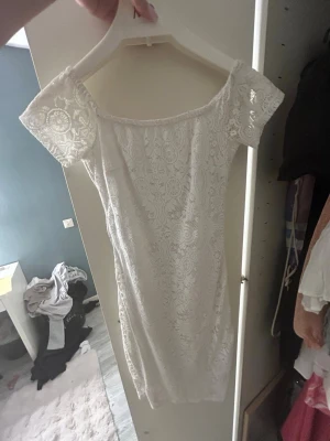 Vit spetsklänning från Gina Tricot - Supersöt vit kortklänning från Gina Tricot i spets med offshoulder och korta ärmar. Klänningen har ett romantiskt mönster och sitter snyggt på kroppen. Perfekt för sommarens alla tillfällen!