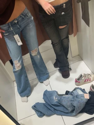 Blå baggy jeans med slitningar - Säljer ett par ljusblå baggy jeans med slitna detaljer på knäna och låren. Jeansen har klassisk femficksmodell, låg midja och råa kanter vid bensluten. Perfekta för en trendig och avslappnad look.