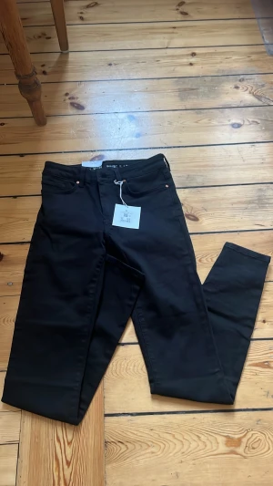 Svarta Peachy Low jeans - Snygga svarta jeans från Peachy Low med låg midja och smal passform. Klassisk femficksmodell och stretchigt material som sitter bekvämt. Perfekta till en avslappnad eller trendig look.