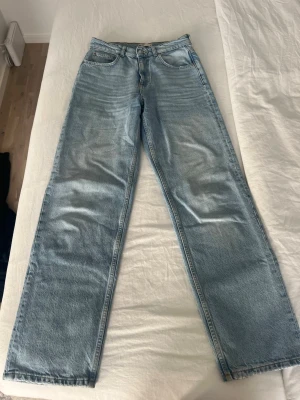 Ljusblå raka jeans - Säljer ett par ljusblå jeans med rak passform och klassisk femficksdesign. Jeansen har normal midja och subtila slitningar framtill för en avslappnad look. Perfekta till sneakers eller boots.