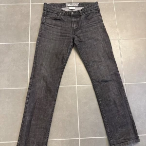 Svarta raka jeans från J.Lindberg  - Säljer ett par svarta raka jeans från J.Lindberg. Jeansen har klassisk femficksdesign, normal midja och dragkedjegylf. Materialet är denim i bomull med en lätt tvättad look. Perfekta för en stilren och avslappnad outfit.