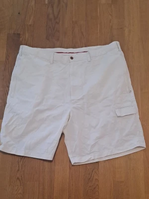 Vita shorts med fickor - Säljer vita shorts från Tommy Hilfiger. De har fickor fram och bak och stängs med knapp och dragkedja.