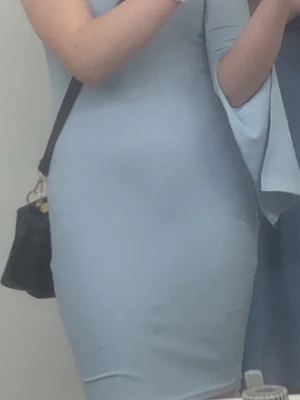 Ljusblå one shoulder klänning - Snygg ljusblå klänning med one shoulder-design och lång ärm. Klänningen är ribbad och har en kort längd som ger en trendig och ungdomlig vibe. Perfekt för dig som gillar stilrena och moderna plagg med en twist. Använd en gång på en skoldans.