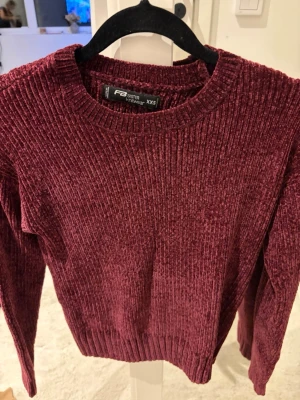 Vinröd chenilletröja från Sister Knitwear - Mysig vinröd stickad tröja från Sister Knitwear i chenillematerial. Tröjan har rund halsringning, ribbade muddar och lång ärm. Perfekt för dig som gillar en mjuk och skön känsla med lite glansig finish.