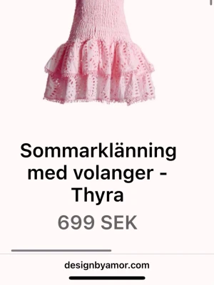 Rosa sommarklänning med volanger - Supersöt rosa kort sommarklänning från Design by Amor med volanger och broderade detaljer. Klänningen har smock upptill och dubbla volanglager nedtill för extra flowy känsla. Perfekt för soliga dagar och midsommar.