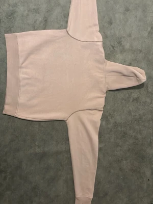 Beige hoodie med huva - Säljer en stilren beige hoodie med huva och ribbade muddar vid ärmslut och nederkant. Hoodien har en klassisk passform och är tillverkad i mjukt material, perfekt för en avslappnad look. Inga synliga loggor eller tryck.