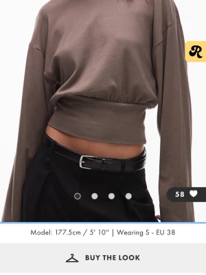 Brun croppad långärmad topp - Trendig brun croppad topp med långa ärmar och bred resår i midjan. Tillverkad i mjukt bomullsmaterial som ger en avslappnad men snygg look. 