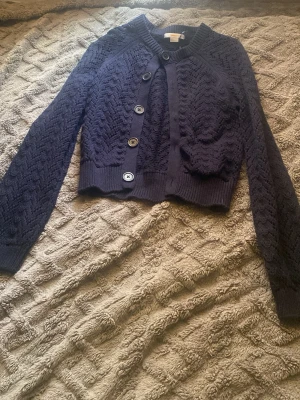 Mörkblå stickad kofta med knappar, pris kan diskuteras  - Snygg mörkblå stickad kofta med zigzag-mönster och stora knappar framtill. Kortare modell med ribbade muddar vid ärmslut och nederkant. Perfekt att slänga över en topp för en trendig lager-på-lager-look.