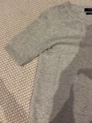 Ljusgrå cashmere tröja - Cashmere tröja från Autograph i 100% cashmere. Tröjan har korta ärmar. Lite sliten i halsringen och därmed sänkt pris. Inget som tänks på. Nypris 1499 kr