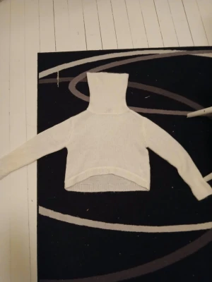 Vit cropped sticad tröja från h&m - Vit stickad cropped sticad tröja från h&m med lång ärm och hög krage. Tröjan har ribbstickade muddar och är perfekt för lager-på-lager-stil. Enkel och clean design som passar till många outfits.