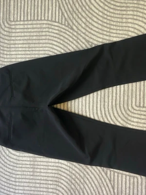 Svarta kostymbyxor från BikBok - Snygga svarta kostymbyxor från BikBok med raka ben och klassisk passform. Byxorna har hällor för bälte, två fickor bak och stängs med dragkedja och knapp. 