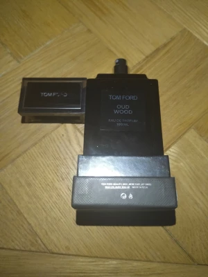 Tom Ford Oud Wood Eau de Parfum 60 ml  - Tom Ford Oud Wood Eau de Parfum 100 ml i en elegant, mörkgrå rektangulär flaska med svart lock. Flaskan har en lyxig och stilren design med märkets logga och doftens namn på framsidan. Perfekt för dig som har gillar exklusiva och träiga dofter. 60 ml kvar 