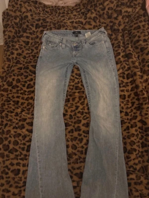 Ljusblå bootcut jeans från true religion  - Säljer ett par ljusblå bootcut jeans från true religion. Storlek W23 finns skavanker vid benslutändan och även en missfärgning fläck på bakfickan som blivit vit då. 