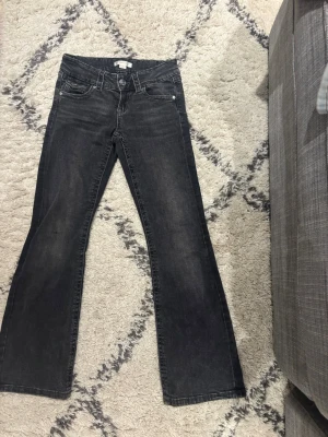 Low waist svarta bootcut jeans 146  - Mörk gråa/svarta jeans strl 146 inte så mycket använda och super sköna. Bootcut med klassiska fem fickor och knappgylf. Jeansen har en lätt tvättad look, bootcut. Perfekta för en avslappnad och trendig stil.