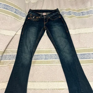 True Religion jeans - Snygga True Religion jeans i mörkblå denim med kontrastsömmar. dekorerade med märkets ikoniska fickdetaljer. Jag köpte de för ett halvår sen men den passade inte min stil så här ingen användning av de och har inte haft det sen jag köpte de igentligen, mitt pris 1400 (storlek W29 L33)