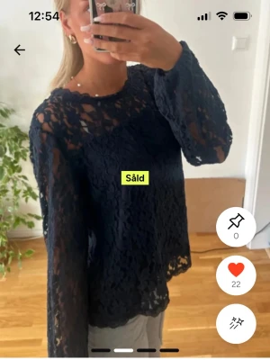 Svart spetsblus med långa ärmar - Snygg svart blus i spets med långärmad modell och rund halsringning. Blusen är genombruten och har en luftig känsla, perfekt att styla med linne under. Passformen är normal och materialet känns lätt och bekvämt.