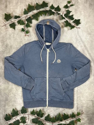 Moncler Maglia Cardigan – Ljusblå – Strl M - |Färg: Ljusblå, tvättad/blekt | Modell: Maglia Cardigan, zip-hoodie | Storlek: M, normal passform | Skick: Grade B, 6,5/10 (blekning) | Hör av dig ifall du har funderingar!