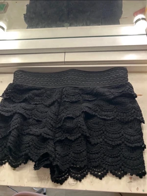 Svarta spets-shorts med volang - Säljer ett par trendiga svarta shorts med flera lager volang i spets. Inga defekter förutom att en tråd låstnat lite där bak i mönstret men absolut inget man märker såg knappt de själv innan jag skulle lägga upp st s/m då de e rätt så stretchiga i bandet där uppe 💞💞💞