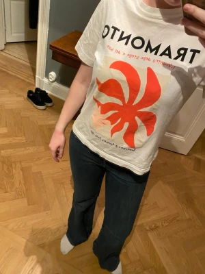 Vit grafisk t-shirt från H&M - Vit t-shirt från H&M med grafiskt tryck i rött och svart framtill. T-shirten har korta ärmar och rund halsringning. Perfekt för en avslappnad och trendig stil.