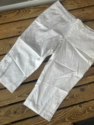 Vita linnebyxor med rak passform - Snygga vita korta byxor med rak och något croppad passform. Byxorna har klassiska fickor fram och hällor för bälte. Perfekta för en fräsch och stilren look under varma dagar.