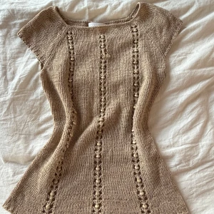 Beige stickad topp från Ruixingdi - Säljer en beige stickad topp från Ruixingdi med korta ärmar och snygga hålmönster i vertikala rader framtill. storleken är oklar men marerialet ät rätt så stretchigt så den passar folk med strl xs till m skulle jag säga. köpte den second hand men av mig är den använd en gång!