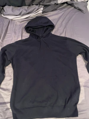 Mörkblå stickad hoodie från RYVLS  - En stilren svart hoodie från RYVLS Stockholm med klassisk huva och dragsnören. Perfekt för dig som gillar en enkel och clean look. Mjuk och skön, passar till det mesta och är lätt att matcha med andra plagg.