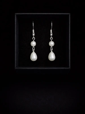 Silverörhängen med vita pärlor - Stilrena örhängen i silver med två vita pärlor på varje, en rund och en droppformad. Perfekt för dig som gillar klassiska smycken med elegant känsla. Hängande modell med krokfäste.